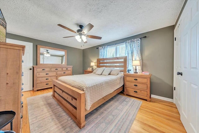 bedroom featuring light wood-style floors, a textured ceiling, baseboards, and a ceiling fan