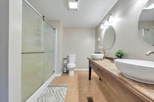 full bath featuring toilet, a shower stall, a sink, and tile patterned floors