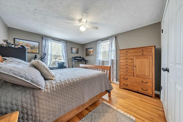 bedroom featuring light wood-style flooring, ceiling fan, and a textured ceiling