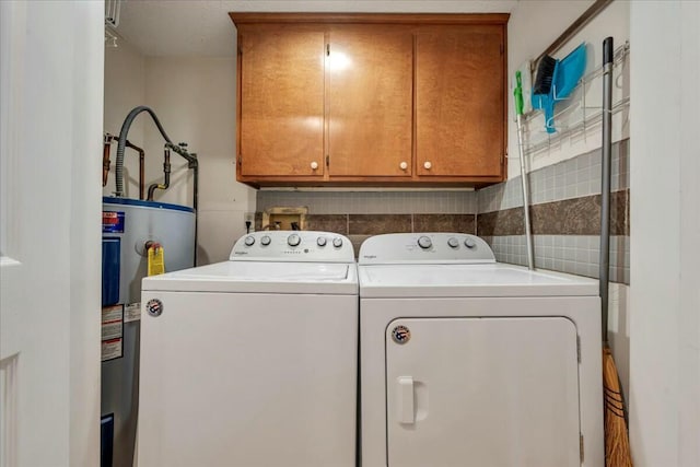 clothes washing area featuring washer and dryer, water heater, and cabinet space