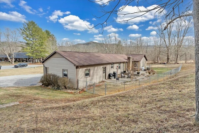 view of side of property with gravel driveway, a fenced backyard, and a patio