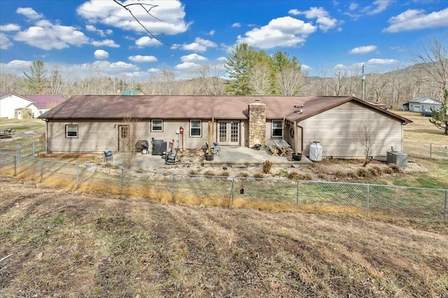 back of house with a fenced backyard, a chimney, french doors, and a patio