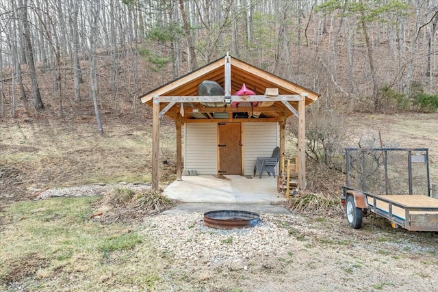 view of outdoor structure with an outdoor fire pit and a forest view