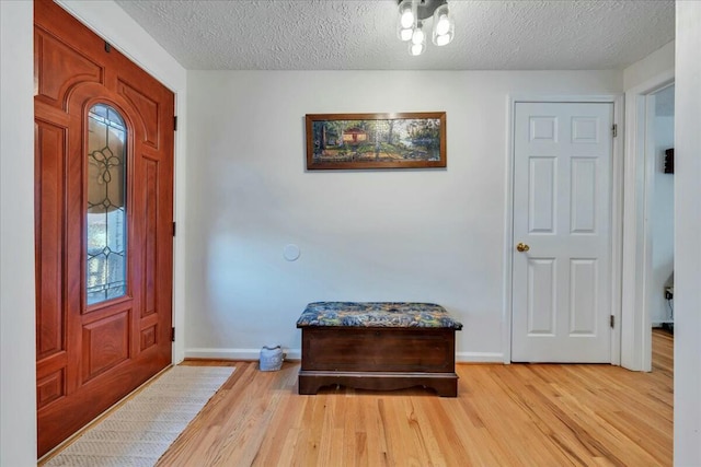 foyer with light wood finished floors, baseboards, and a textured ceiling