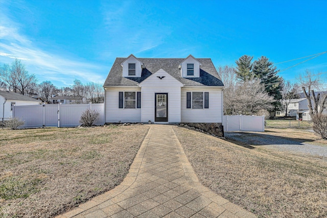 cape cod house featuring a gate, roof with shingles, fence, and a front lawn