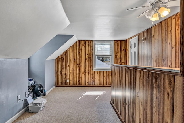 additional living space featuring carpet flooring, vaulted ceiling, wooden walls, ceiling fan, and baseboards