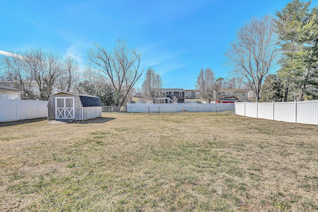 view of yard with an outbuilding, a fenced backyard, and a shed