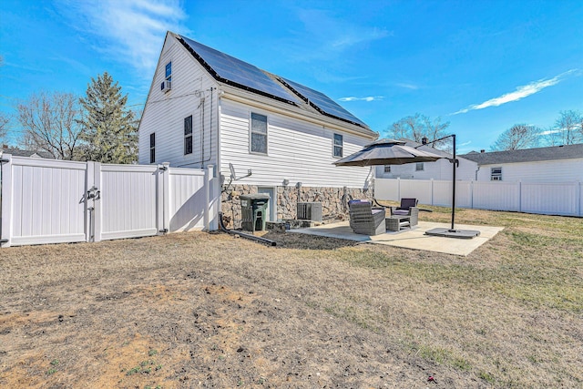 back of house featuring a lawn, a patio area, a fenced backyard, and a gate