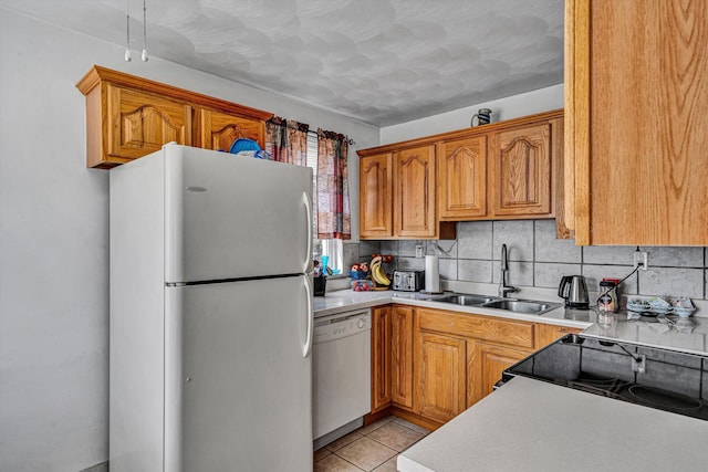 kitchen featuring white appliances, tasteful backsplash, light tile patterned floors, light countertops, and a sink