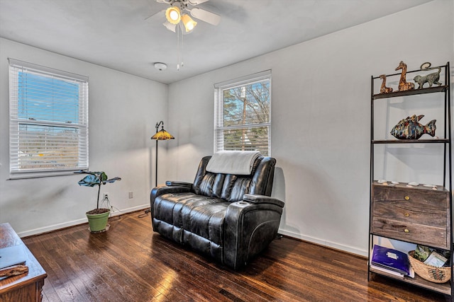 living area with a ceiling fan, hardwood / wood-style flooring, and baseboards