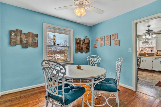 dining room featuring a healthy amount of sunlight, hardwood / wood-style flooring, and baseboards