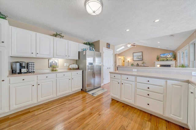 kitchen featuring a ceiling fan, stainless steel fridge, light wood-style floors, light countertops, and vaulted ceiling