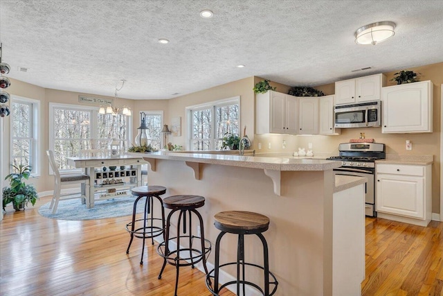 kitchen featuring a kitchen breakfast bar, stainless steel appliances, light countertops, and light wood-style floors