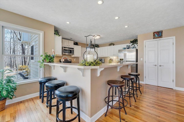 kitchen with a peninsula, stainless steel appliances, light countertops, and light wood-style floors