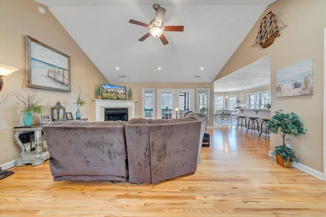 living room with a fireplace, baseboards, a ceiling fan, and wood finished floors