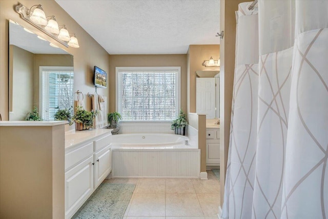 bathroom with tile patterned floors, a textured ceiling, vanity, and a bath