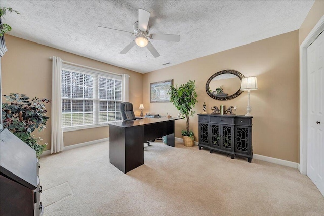 carpeted home office featuring a textured ceiling, visible vents, baseboards, and ceiling fan