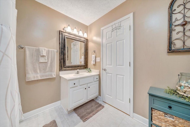 bathroom featuring tile patterned floors, baseboards, a textured ceiling, and vanity