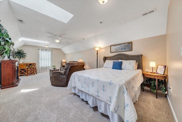 bedroom featuring lofted ceiling with skylight, carpet, visible vents, and a textured ceiling