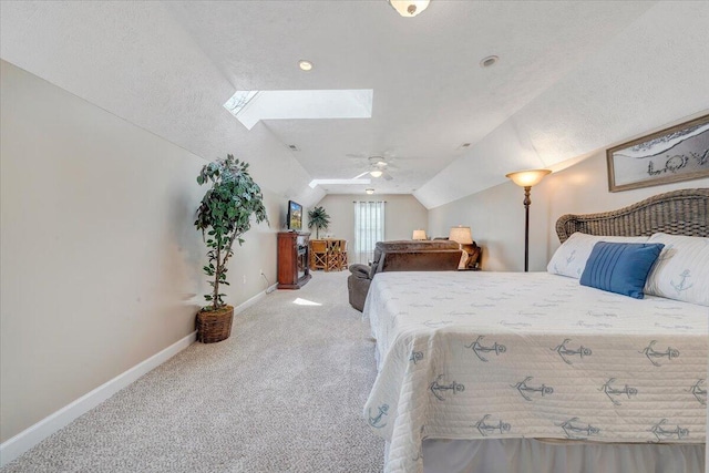 carpeted bedroom featuring vaulted ceiling with skylight, a ceiling fan, and baseboards