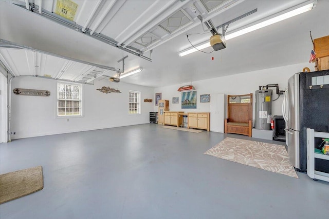 garage featuring a garage door opener, water heater, and freestanding refrigerator