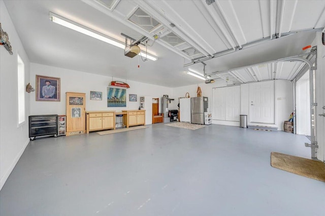 garage with a garage door opener, freestanding refrigerator, and baseboards