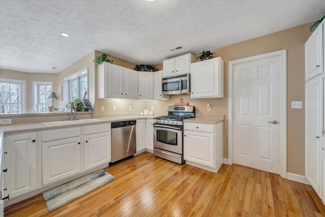 kitchen with visible vents, a sink, light wood-style floors, appliances with stainless steel finishes, and light countertops