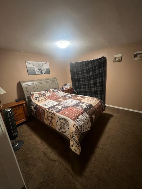 bedroom with baseboards and dark carpet