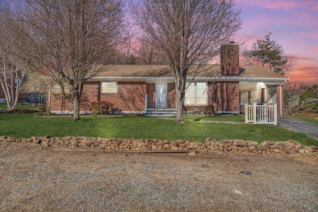 single story home featuring a yard, brick siding, and a chimney