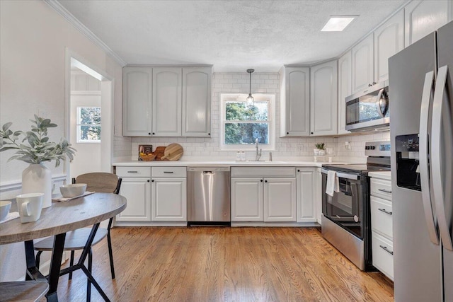 kitchen with a sink, tasteful backsplash, appliances with stainless steel finishes, and light wood-style flooring