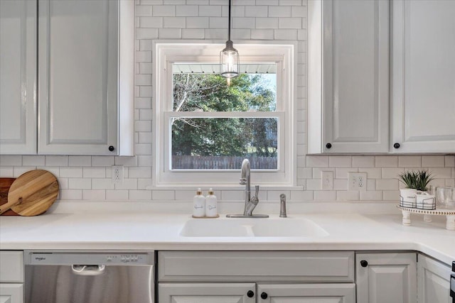 kitchen with white cabinetry, a sink, decorative backsplash, light countertops, and stainless steel dishwasher