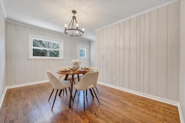 dining room with a chandelier, baseboards, wood finished floors, and crown molding