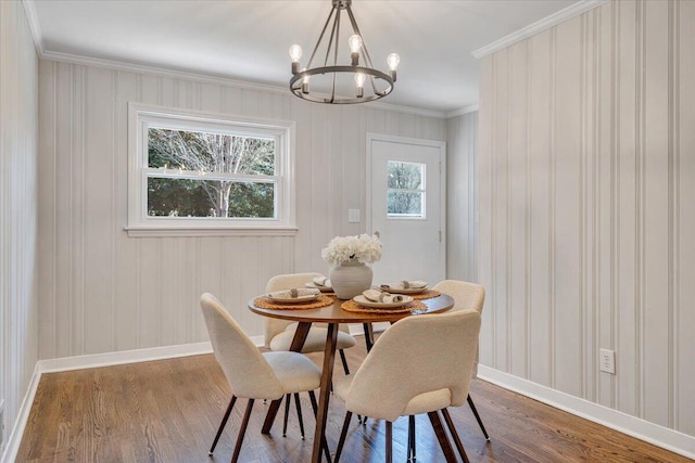 dining room with a chandelier, ornamental molding, baseboards, and wood finished floors