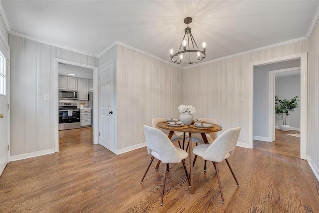 dining room with an inviting chandelier, crown molding, and wood finished floors