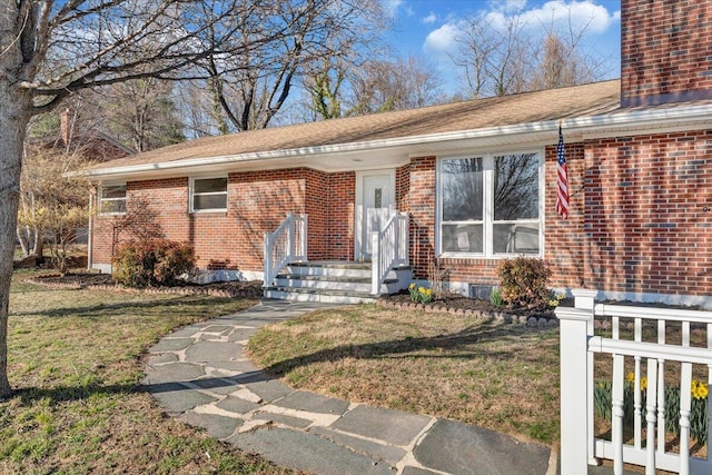 single story home with brick siding, a chimney, and a front lawn