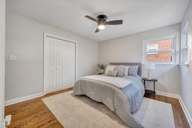 bedroom featuring a closet, baseboards, wood finished floors, and a ceiling fan