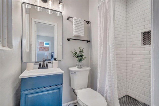 bathroom with toilet, vanity, and a tile shower