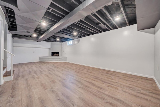 below grade area with a fireplace, baseboards, and wood finished floors