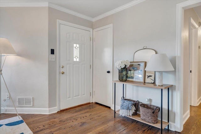 foyer entrance featuring visible vents, baseboards, wood finished floors, and ornamental molding