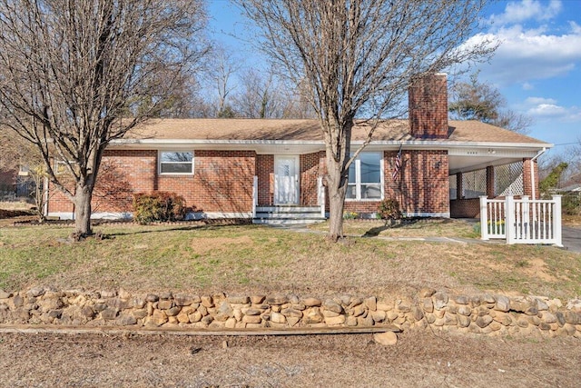 single story home featuring a carport, a front lawn, brick siding, and a chimney