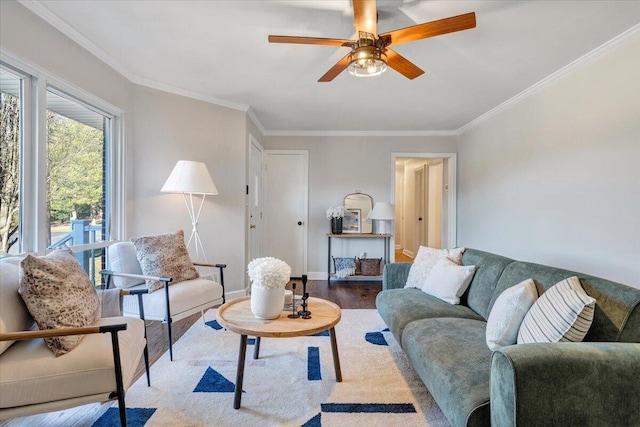 living area with ornamental molding, a ceiling fan, baseboards, and wood finished floors