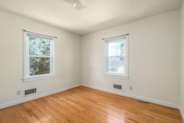 empty room featuring baseboards, visible vents, and light wood-type flooring