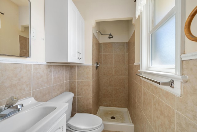 bathroom with a shower stall, a wainscoted wall, toilet, vanity, and tile walls