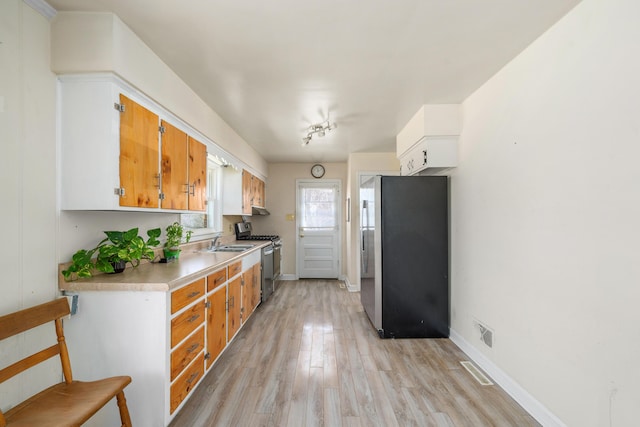 kitchen with visible vents, light wood-style flooring, a sink, stainless steel appliances, and light countertops