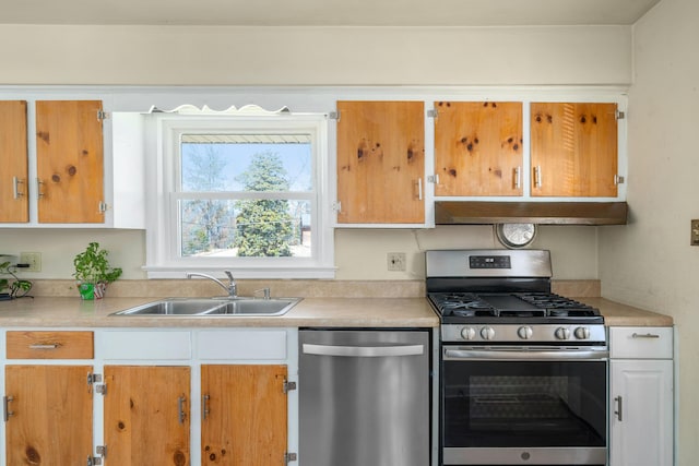 kitchen featuring under cabinet range hood, appliances with stainless steel finishes, light countertops, and a sink