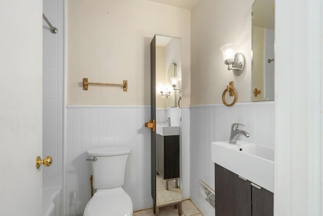 full bathroom with vanity, tile patterned floors, toilet, and a wainscoted wall