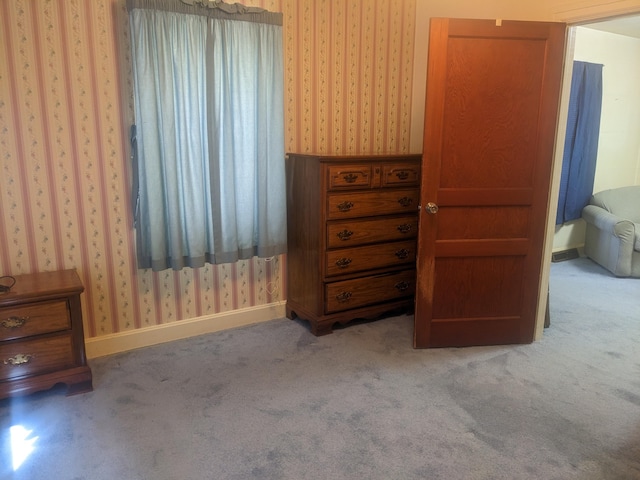 unfurnished bedroom with baseboards, wallpapered walls, and carpet