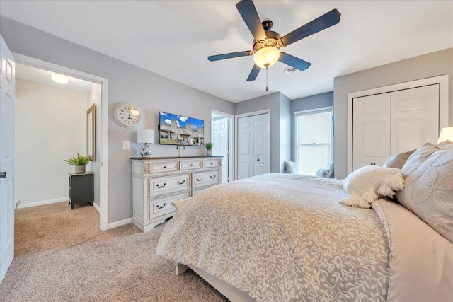 bedroom featuring visible vents, light carpet, multiple closets, baseboards, and ceiling fan