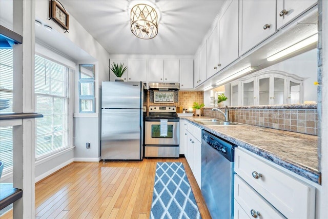 kitchen featuring backsplash, light wood-type flooring, stainless steel appliances, white cabinetry, and a sink