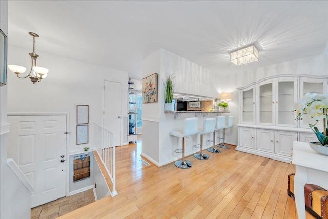 kitchen featuring a kitchen bar, light wood-style floors, white cabinetry, and a chandelier